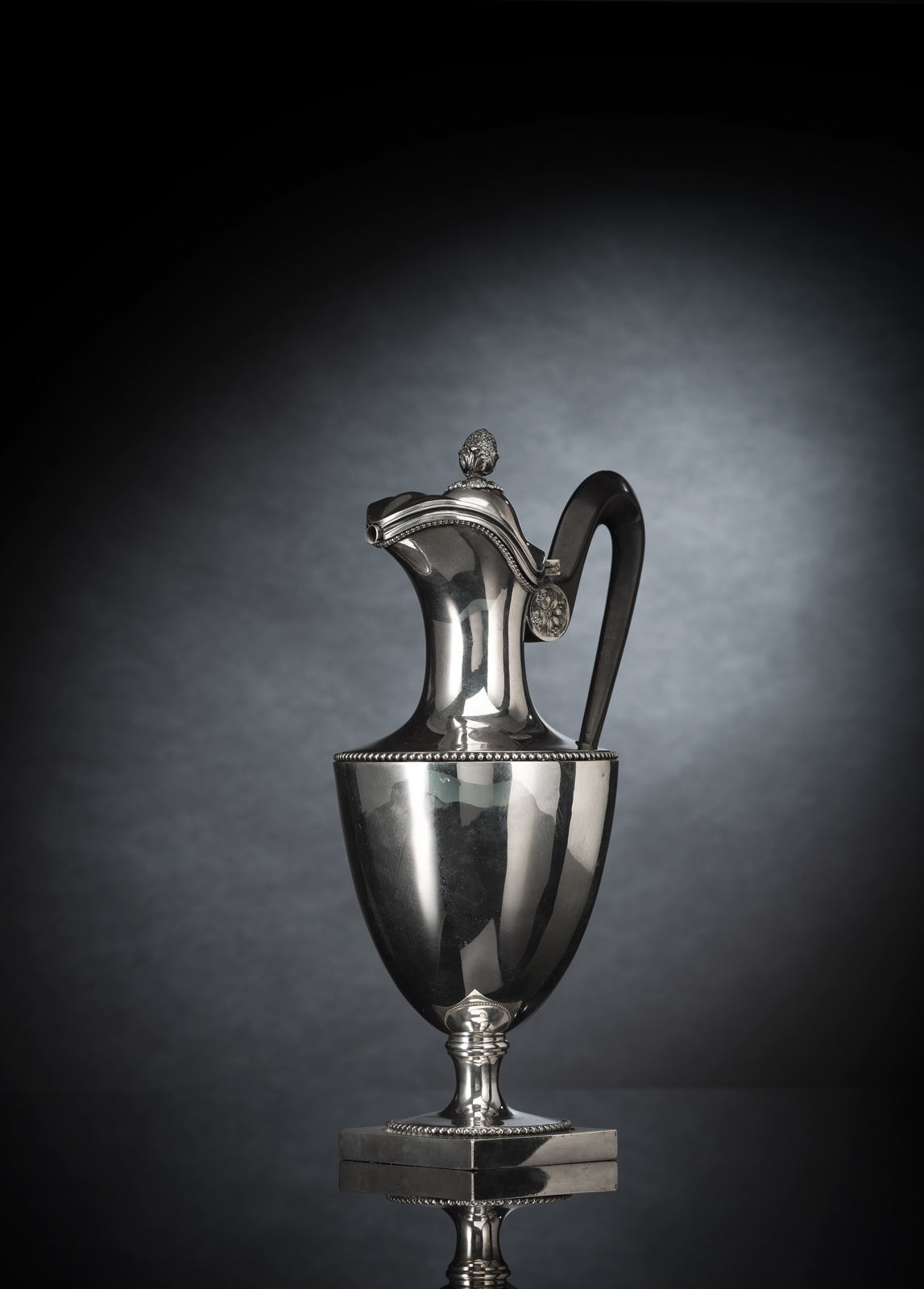 Silber, ovoider Korpus mit Perlbandfriesen, Röhrenausguss und ebonisiertem Holzhenkel. Feingehaltsstempel für 800er Silber mit Hahn, Meisterzeichen wohl von Gabriel Germain Dutalis (?, etwas verschlagen). 784 gr. Minim. verbeult.